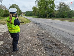 zdjęcie przedstawiające policjanta Ruchu Drogowego podczas wykorzystania urządzenia do pomiaru prędkości