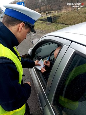 zdjęcie przedstawiające policjanta Ruchu Drogowego wraz z kierującym, który podpisuje mandat karny