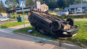 Na zdjęciu widoczny pojazd leżący na dachu przed przejściem dla pieszych. W tle widoczny radiowóz i kilka osób.