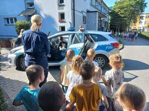 Zdjęcie przedstawiające policjantkę oraz dzieci oglądające radiowóz.