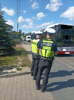 Zdjęcie kolorowe przedstawiające policjantów ruchu drogowego w trakcie obserwacji kierujących samochodami.