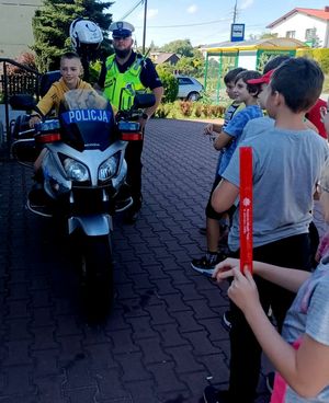 Zdjęcie przedstawiające policjanta, dzieci oraz dziecko na motocyklu policyjnym