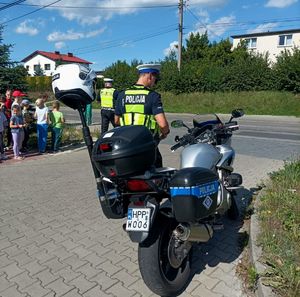 Zdjęcie przedstawiające policjantów, dzieci oraz policyjny motocykl.