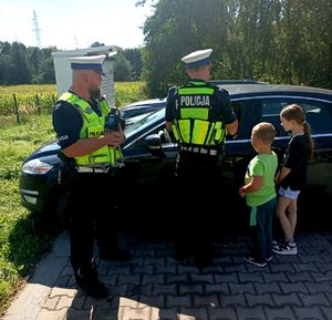 Zdjęcie przedstawiające policjantów i dzieci w trakcie kontroli drogowej.