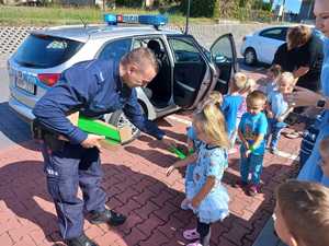 Zdjęcie przedstawiające dzielnicowego przekazującego dzieciom odblaski.