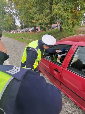 Zdjęcie przedstawiające policjanta ruchu drogowego wręczającego odblask.