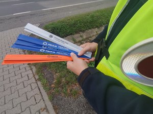 Zdjęcie przedstawiające policjanta ruchu drogowego trzymającego odblaski.