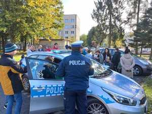 Zdjęcie przedstawiające policjanta, radiowóz oraz dzieci.