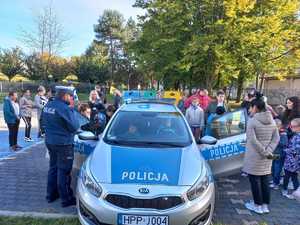 Zdjęcie przedstawiające policjanta oraz dzieci oglądające radiowóz.