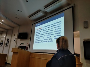 Zdjęcie przedstawiające nadkomisarz  Anetę Zacharjasz w trakcie omawiania wyświetlanego slajdu.