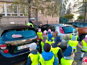 Zdjęcie przedstawiające policjanta ruchu drogowego oraz dzieci w trakcie kontroli drogowej.