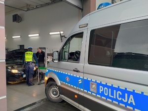 Zdjęcie przedstawiające policjanta, Pana Diagnostę oraz radiowóz.