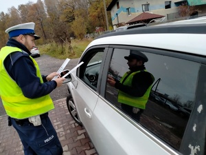 Zdjęcie policjanta ruchu drogowego wręczającego kierowcy odblask.