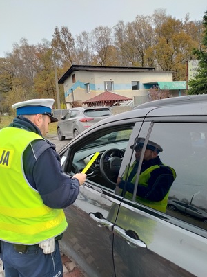 Zdjęcie policjanta ruchu drogowego wręczającego kierowcy odblask.