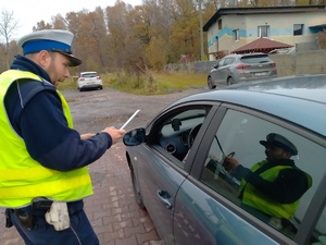 Zdjęcie policjanta ruchu drogowego wręczającego kierowcy odblask.