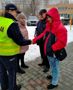 Zdjęcie przedstawiające policjantkę, pracownice Ośrodka Opieki Społecznej  w momencie podawania ręki przez policjantkę jednemu z mężczyzn.