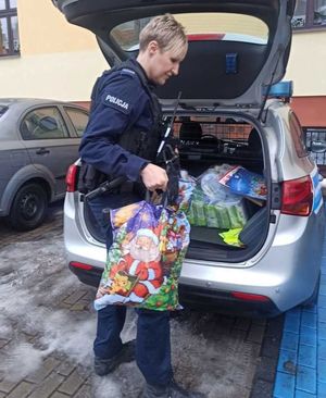 Zdjęcie przedstawiające policjantkę niosącą prezenty.