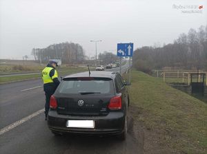 Zdjęcie przedstawiające policjanta, który kontroluje samochód osobowy.