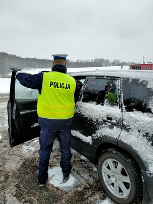 Zdjęcie policjanta w trakcie badania stanu trzeźwości kierowcy.