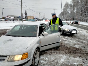 Zdjęcie policjanta w trakcie badania stanu trzeźwości kierowcy.