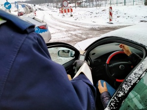 Zdjęcie policjanta w trakcie badania stanu trzeźwości kierowcy.