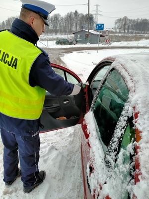 Zdjęcie policjanta w trakcie badania stanu trzeźwości kierowcy.