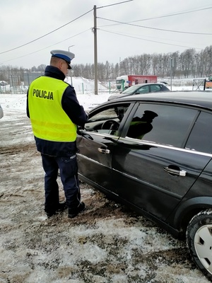 Zdjęcie policjanta w trakcie badania stanu trzeźwości kierowcy.