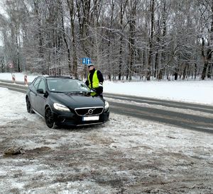 Zdjęcie policjanta w trakcie badania stanu trzeźwości kierowcy.