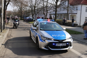 Zdjęcie przedstawiające radiowóz w trakcie zabezpieczenia przemarszu uczniów.