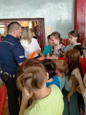 Zdjęcie przedstawiające policjanta rozdającego odblaski.