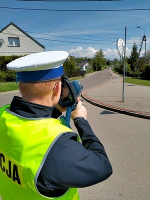 Zdjęcie przedstawiające policjanta ruchu drogowego trzymającego radar.