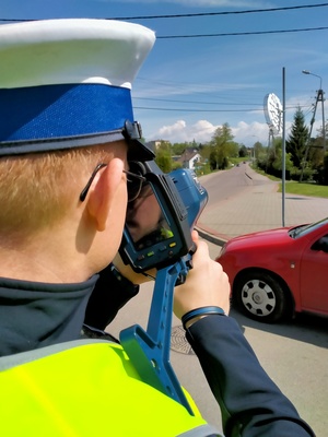 Zdjęcie przedstawiające policjanta ruchu drogowego trzymającego radar.