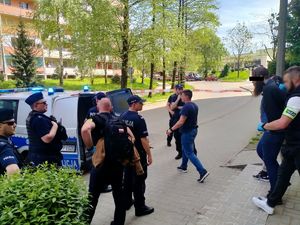 Zdjęcie przedstawiające policjantów, radiowóz oraz osobę zatrzymaną.