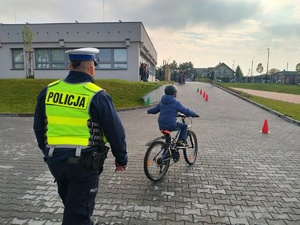 Zdjęcie przedstawiające policjanta oraz ucznia, który wskazuje manewr skrętu w lewo.