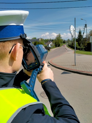 Zdjęcie policjanta dokonującego pomiaru prędkości.