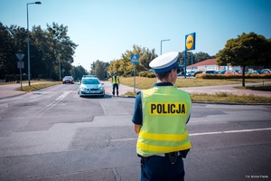 Zdjęcie przedstawiające policjanta ruchu drogowego oraz radiowóz policyjny.