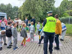 Zdjęcie przedstawiające policjantów oraz uczniów w trakcie korzystania z miasteczka ruchu drogowego.