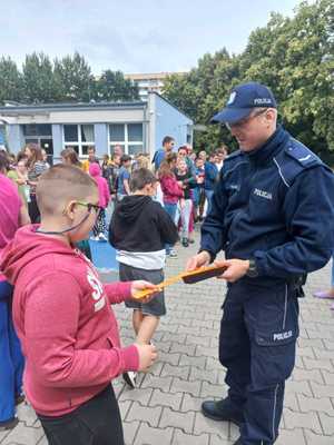 Zdjęcie przedstawiające policjanta w trakcie wręczania odblasku chłopcu.