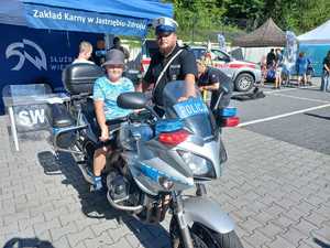 Zdjęcie motocykla policyjnego, policjanta oraz dzieci.