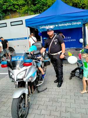 Zdjęcie motocykla policyjnego, policjanta oraz dzieci.