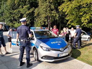 Zdjęcie przedstawiające policjantów, radiowóz oraz uczestników.