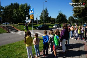 Zdjęcie przedstawiające policjanta oraz dzieci przy przejściu dla pieszych.