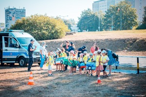 Zdjęcie przedstawiające policjantów, radiowóz oraz przedszkolaki.