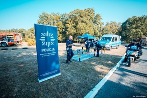 Zdjęcie przedstawiające policjantów oraz dzieci bawiące się miasteczkiem ruchu drogowego.