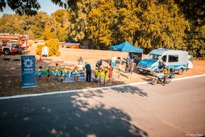 Zdjęcie przedstawiające policjantów i dzieci bawiące się mobilnym miasteczkiem.