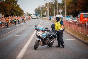 Zdjęcie przedstawiające policjanta oraz motocykl oraz uczestników.