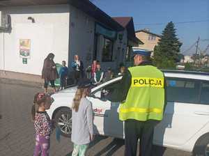 Zdjęcie przedstawiające policjanta, który w obecności dzieci bada kierowcę.