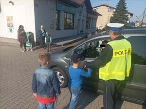 Zdjęcie przedstawiające dzieci i policjanta w trakcie badania stanu trzeźwości.