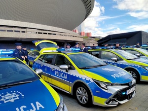 Zdjęcie przedstawiające policjantów i Pana zaproszonych gości przy radiowozach.