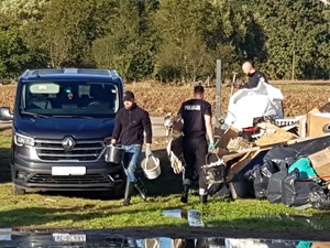 Zdjęcie przedstawiające policjantów noszących rzeczy do wyrzucenia.